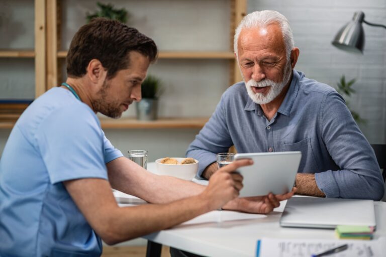 Two men looking at a tablet together, discussing whether testosterone replacement therapy (TRT) is covered by insurance.