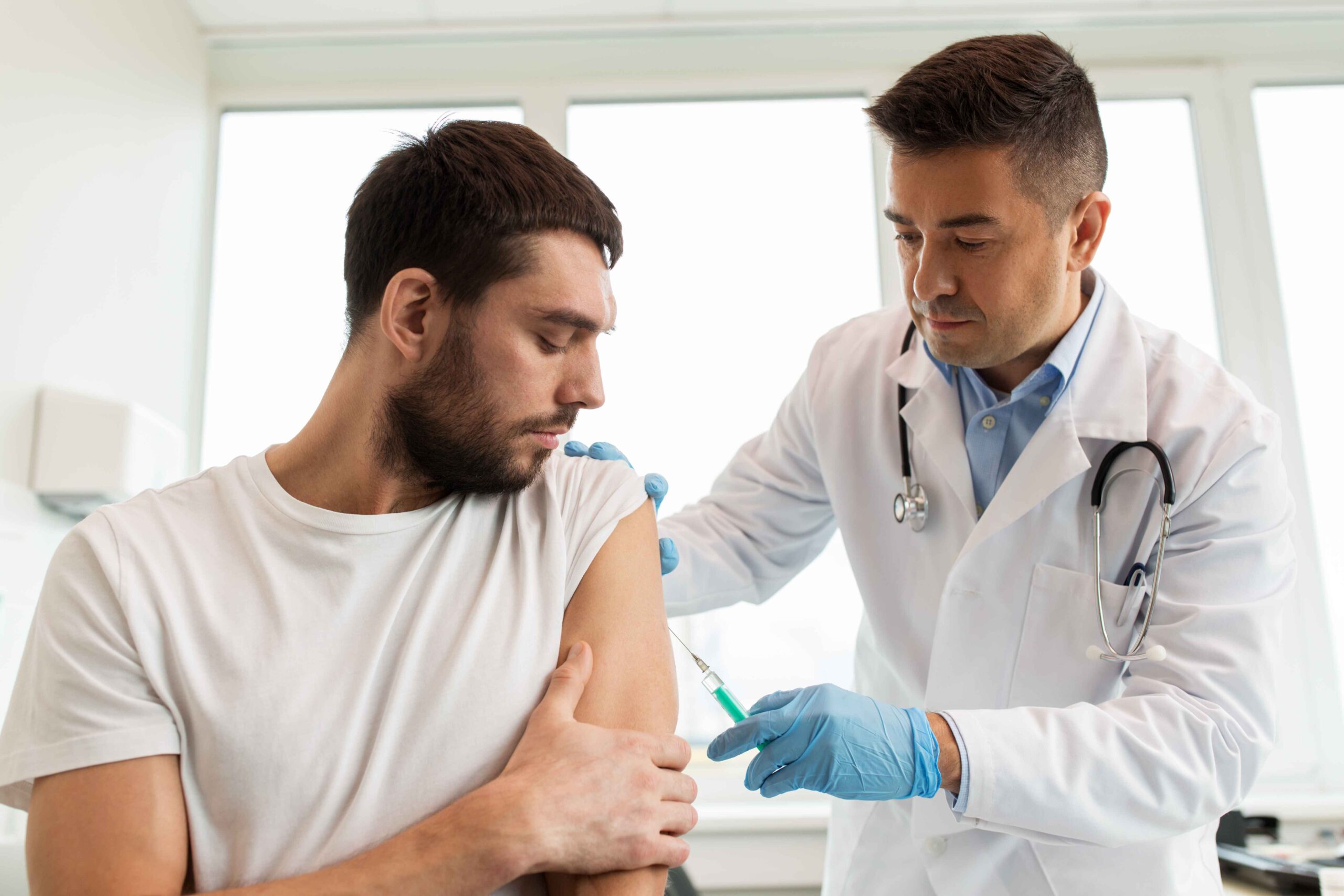 Doctor administering a Vitamin B12 injection to a male patient, receiving professionally administered dosages at their.