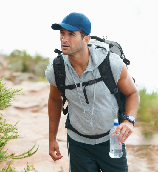 Man hiking with a backpack and water bottle, representing active lifestyle benefits from testosterone therapy.