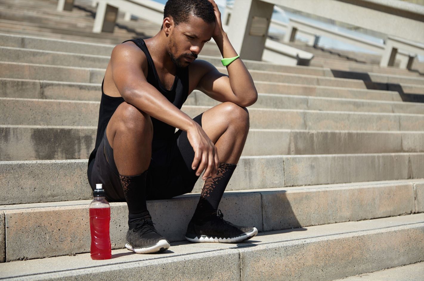 Man sitting on the stairs, thinking about whether pre-workout supplements could cause erectile dysfunction.